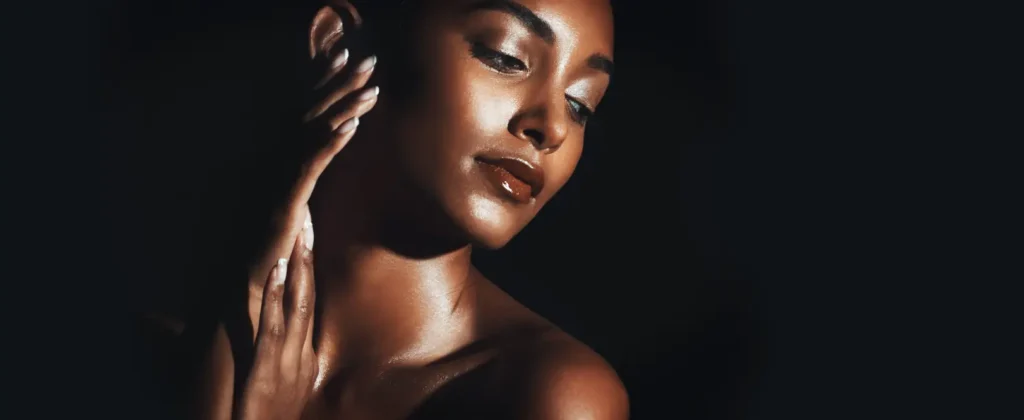 Close-up portrait of a woman with illuminated skin against a dark background.