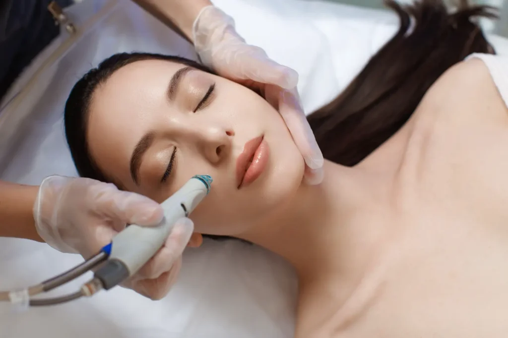 Person receiving a HydraFacial treatment while lying on a treatment bed.