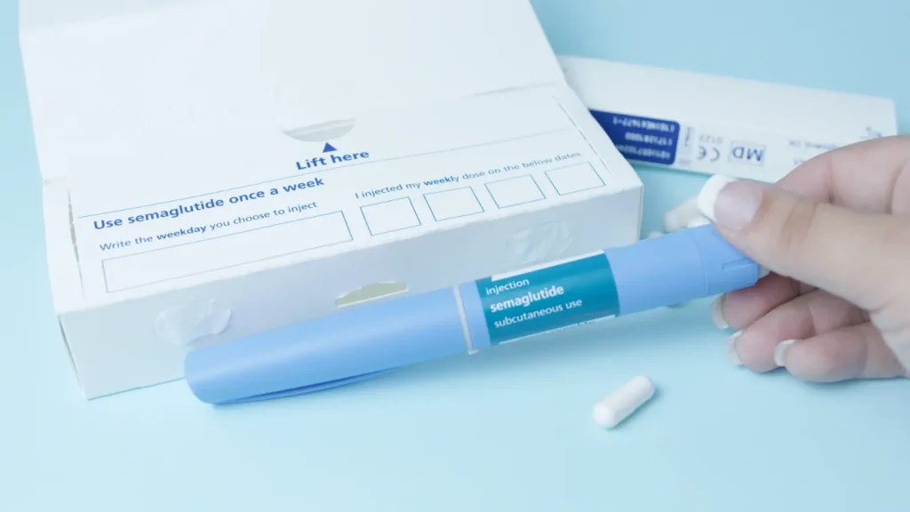 Hand holds a blue semaglutide injection pen beside packaging with weekly dosing instructions.